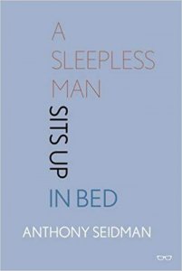 A sleepless man sits up in bed